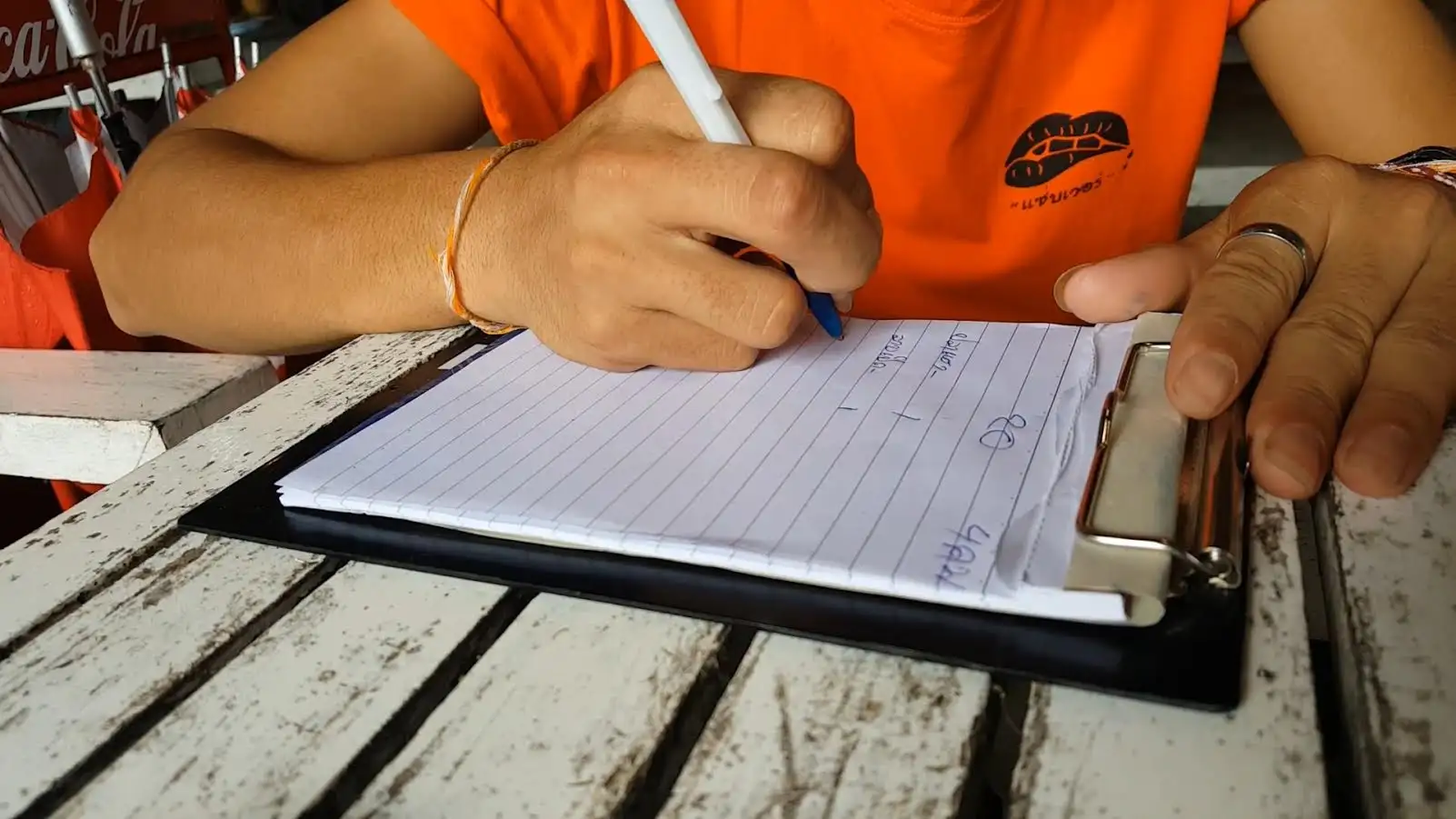 พันนี้กะยัง เด็กเสิร์ฟชาวลาวพลิกสมุดเขียนภาษาไทยรับออเดอร์อย่างคล่องแคล่ว